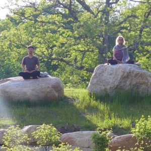 Two people meditate on rocks