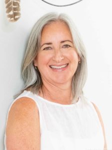 Smiling woman with grey hair in white sleeveless dress