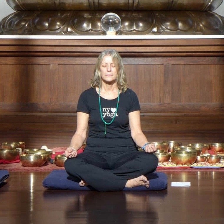 Blond woman in black tshirt and yoga pants meditating