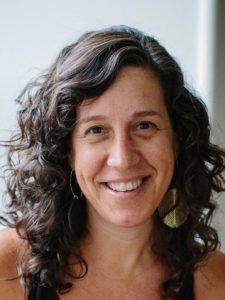 Close-cropped image of smiling woman with dark curly hair