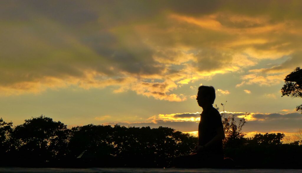 Seated man silhouetted at sunset