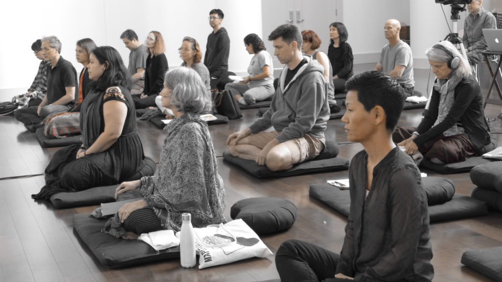 a group of people sitting on meditation cushions