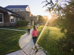 People walk around a coutryard as the sunlight shines