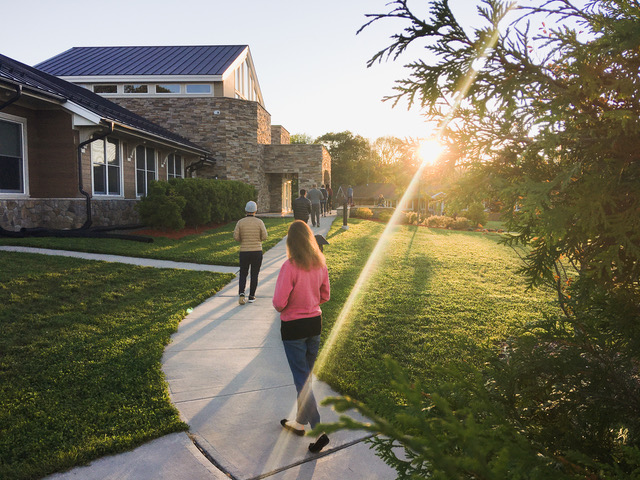 People walk around a courtyard as the sunlight shines