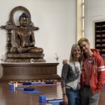 A mand and a woman smiling and hugging in front of a Buddha