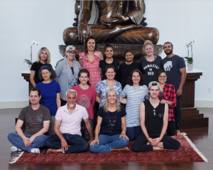 A group of people standing in front of a Buddha statue
