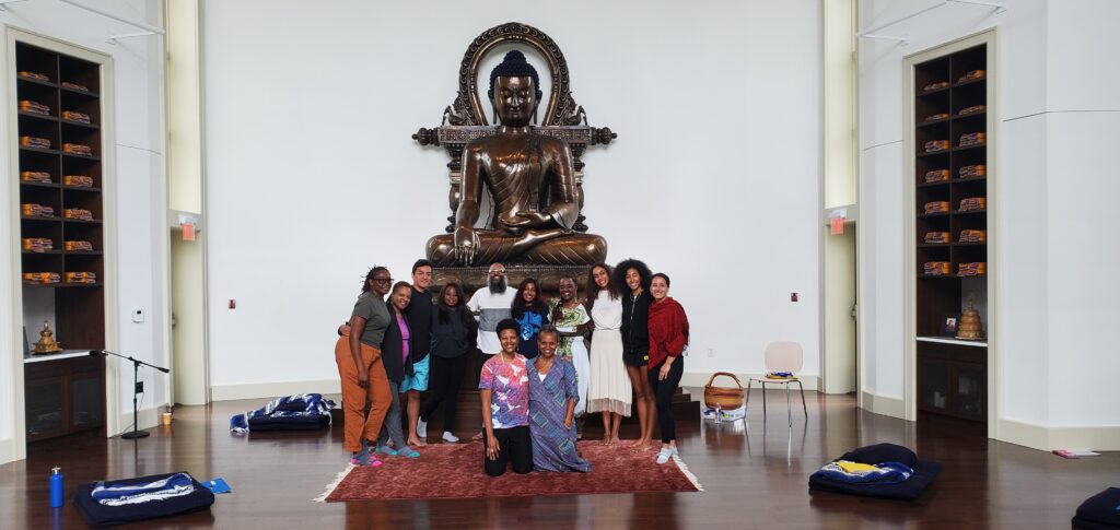 group of BIPOC people in front of a Buddha