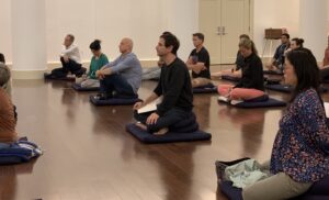 people on mediation cushions listening to a teacher