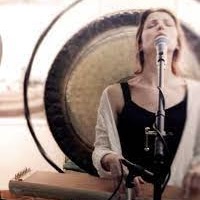 woman in front of a gong with microphone