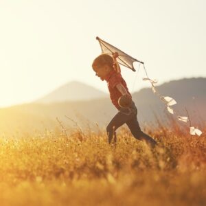 child running with a kite in a field
